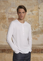 Model is wearing a white long sleeve henley t-shirt in pima cotton.