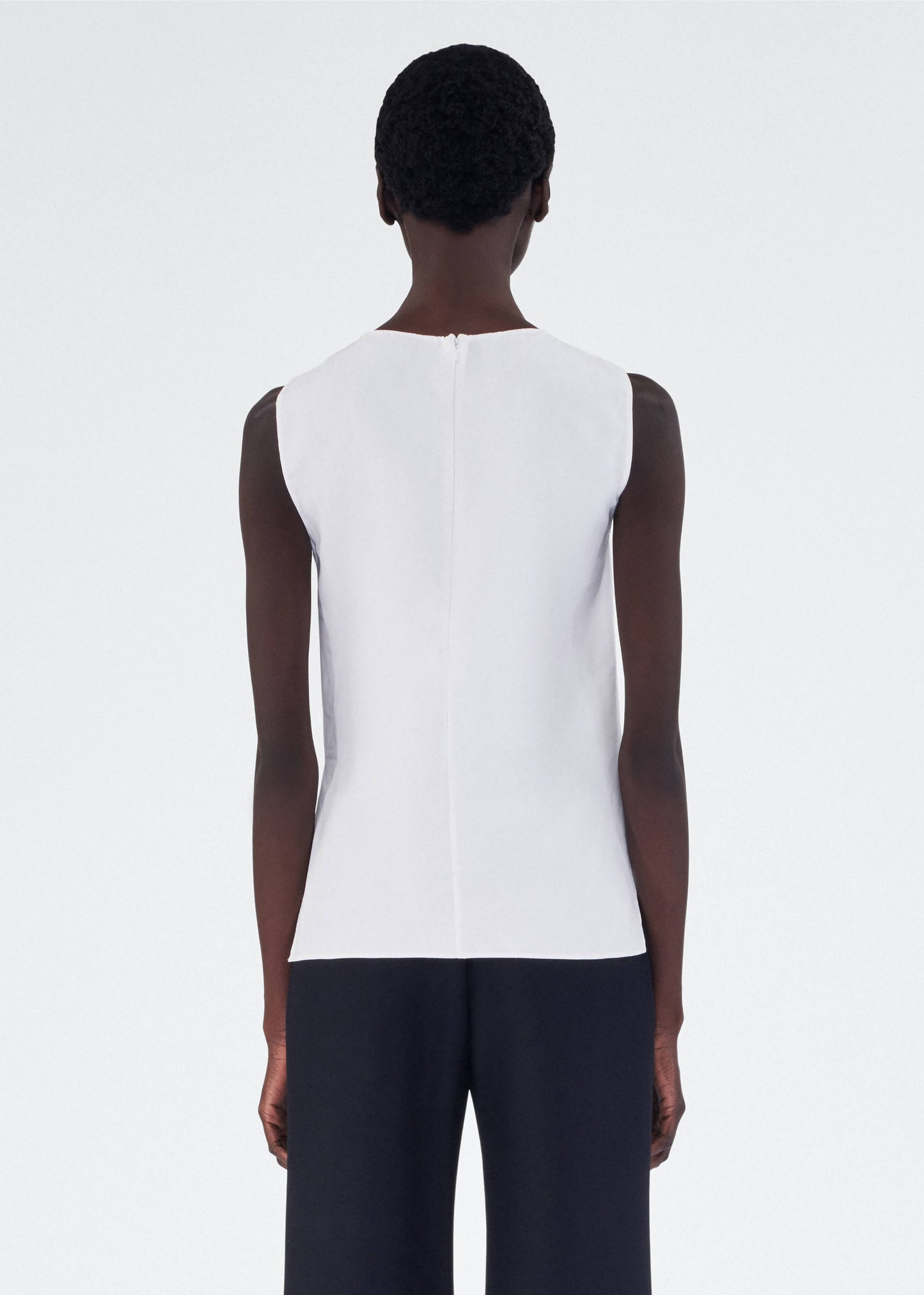 back view of model wearing feyda top by adam lippes in compact cotton poplin in white