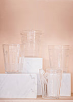 Four crystal cups in front of a pale pink background