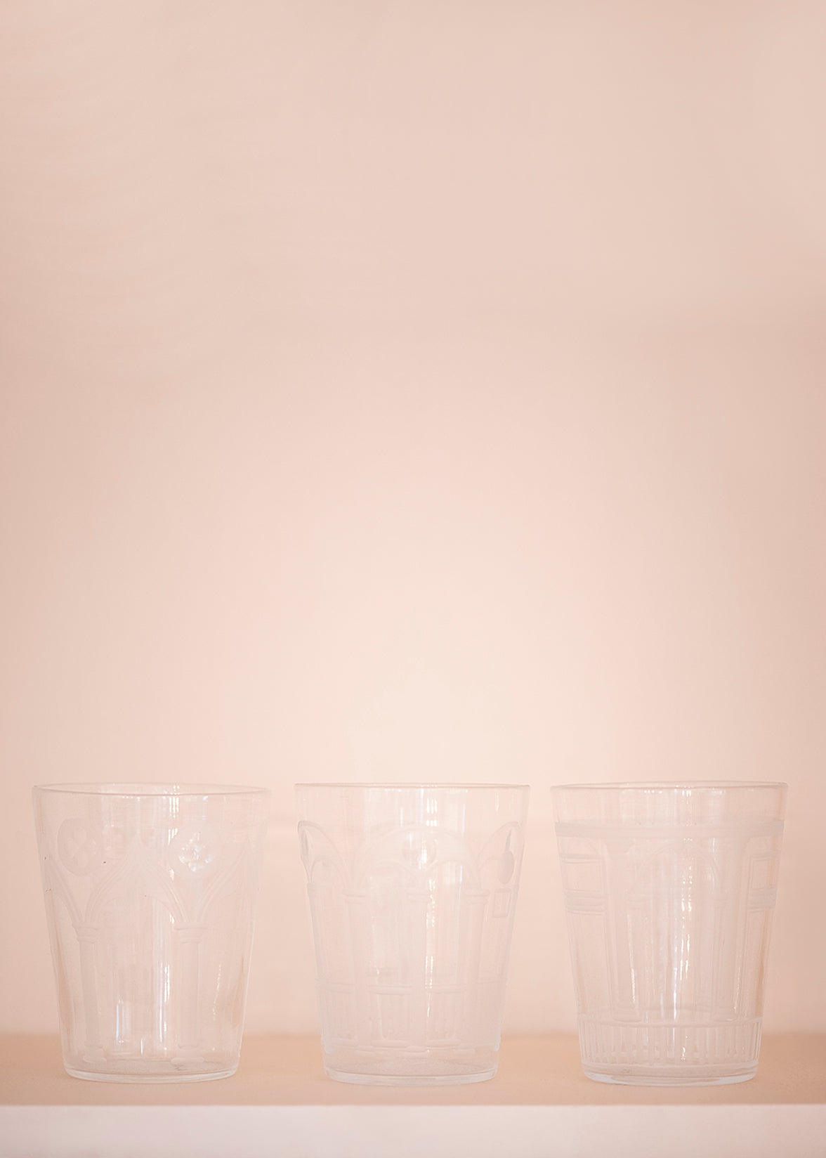 Three crystal cups in front of pale pink background