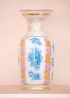 An image of a glass vase with painted blue, gold, and pink florals. 