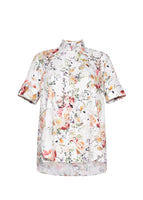 A flat lay of a short sleeve white floral trapeze top. 