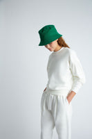 A model wearing a white sweatsuit and green bucket hat.