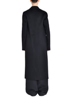 A back angle of a model wearing a black long zibeline cashmere coat over an all black outfit.
