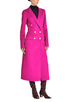 A side-facing photo of a model wearing a hot pink coat with gold buttons and tall brown boots.