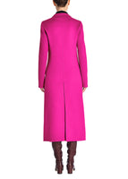 A back-facing image of a model wearing a hot pink coat with gold buttons and tall brown boots.