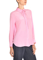 A side angle of a model wearing a pink tie neck top.