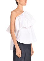 A side angle of a model wearing a one shoulder white poplin ruffle top with a ruffle.