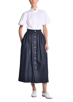 A model wearing a navy skirt with pearl buttons. 
