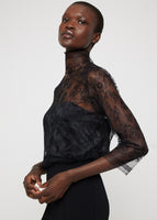 A model wearing a black lace turtleneck top.