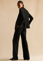 A model turned to the back and wearing a black linen suit.