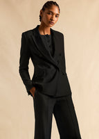 A model with her hand in her pocket wearing a black linen suit and button down black sweater.