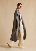 A model turned to the side wearing a grey zibeline cashmere coat with patch pockets.