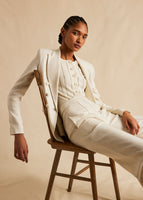 A side view campaign image of a model wearing in ivory suit. 