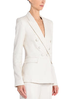 A side view image of a model wearing an ivory, double breasted blazer. 