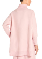 A back angle of a model wearing a pink turtleneck sweater.