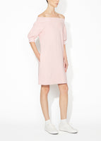 An angled view of a blush off the shoulder dress.