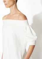 A detailed view of an ivory off the shoulder dress.