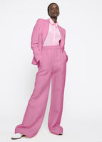 A model wearing a pink suit with a pink shirt tucked in.