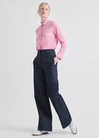 A model wearing a pink tie neck top tucked into a pair of jeans.