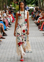 A runway image of a model wearing a red, floral, embroidered, midi dress. 